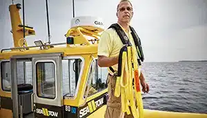 sea tow captain holding extra line-rope on boat